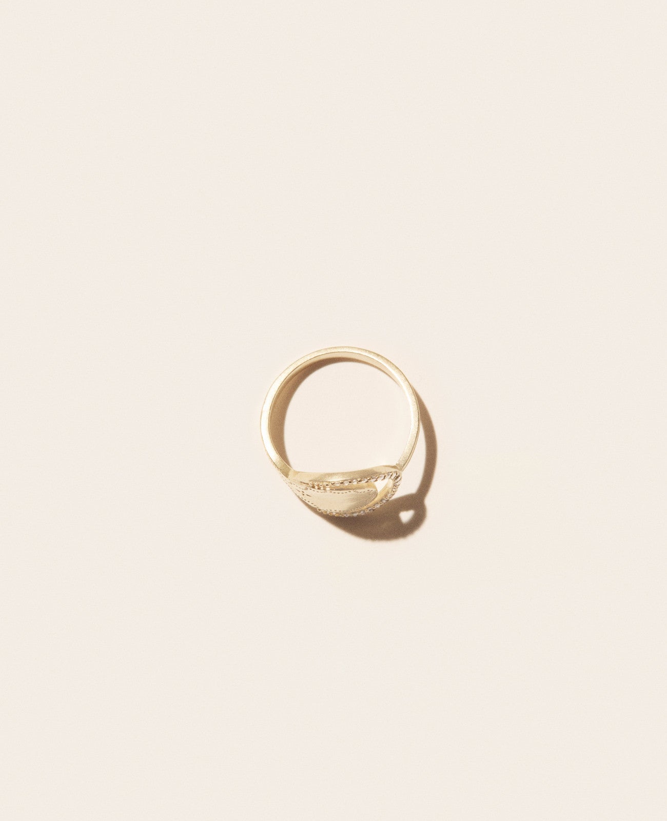 The Rio Ring by Pascale Monvoisin is a single gold ring featuring a flat, textured top that casts a shadow on a plain, light background.