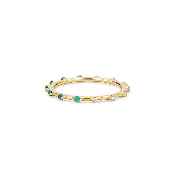 The Two-Toned Stacker Ring by Kate Collins Jewelry is a thin gold band with alternating small green and clear white gemstones. Its elegant design, ideal for colorful stacking, is showcased on a plain white background.