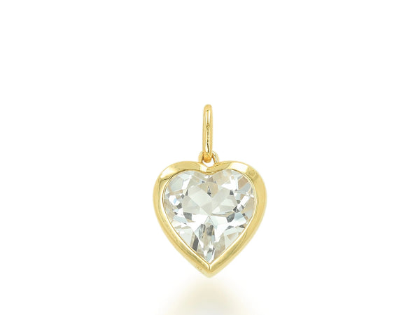 The Rachel Reid Gemstone Heart Charm is a 14k yellow gold pendant with a heart-shaped clear gemstone set in a gold bezel, shown on a plain white background—an elegant accessory for any occasion.