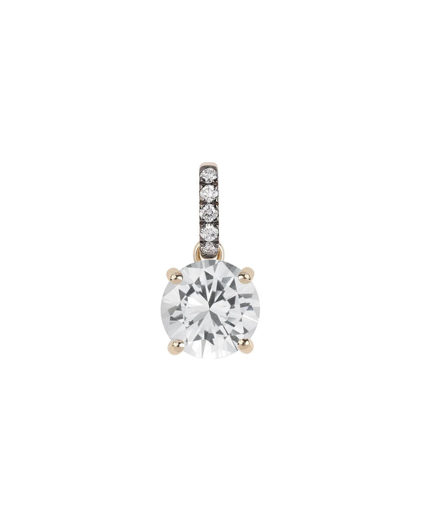 The Rachel Reid Gemstone Charm is a 14k gold pendant with a large round clear gemstone in four prongs, accented by small diamonds on the bail—ideal for layering—shown against a white background.