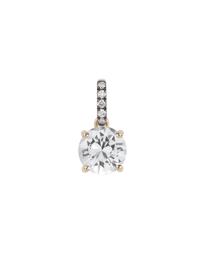 The Rachel Reid Gemstone Charm is a 14k gold pendant with a large round clear gemstone in four prongs, accented by small diamonds on the bail—ideal for layering—shown against a white background.