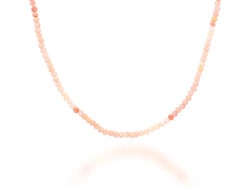 The 28 Gemstone Bead Necklace by Rachel Reid features small, round gradient pink and peach beads delicately arranged in a gentle curve against a white background.