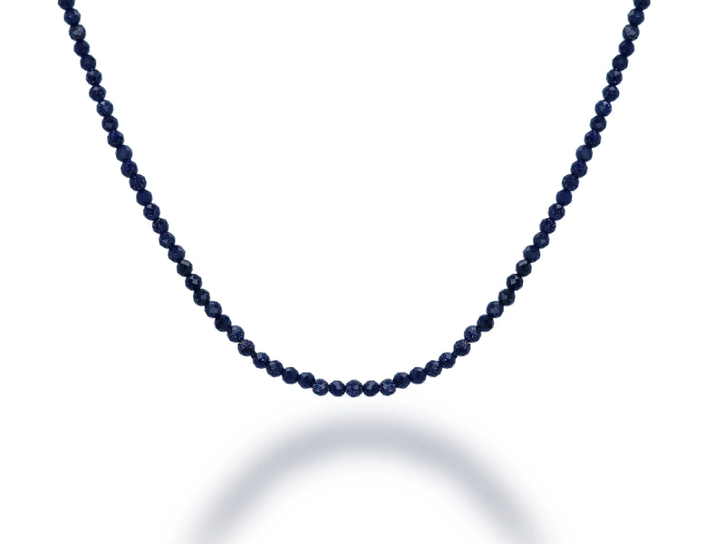 The Rachel Reid 28 Gemstone Bead Necklace features small, round dark blue beads strung closely together with a secure lobster claw closure, displayed in a gentle curve against a white background with a subtle shadow.