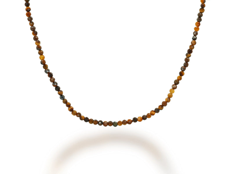A close-up of the Rachel Reid 28 Gemstone Bead Necklace shows small, round beads in brown, amber, and gold tones arranged symmetrically on a white background, with optional 14K yellow gold accents for extra elegance.