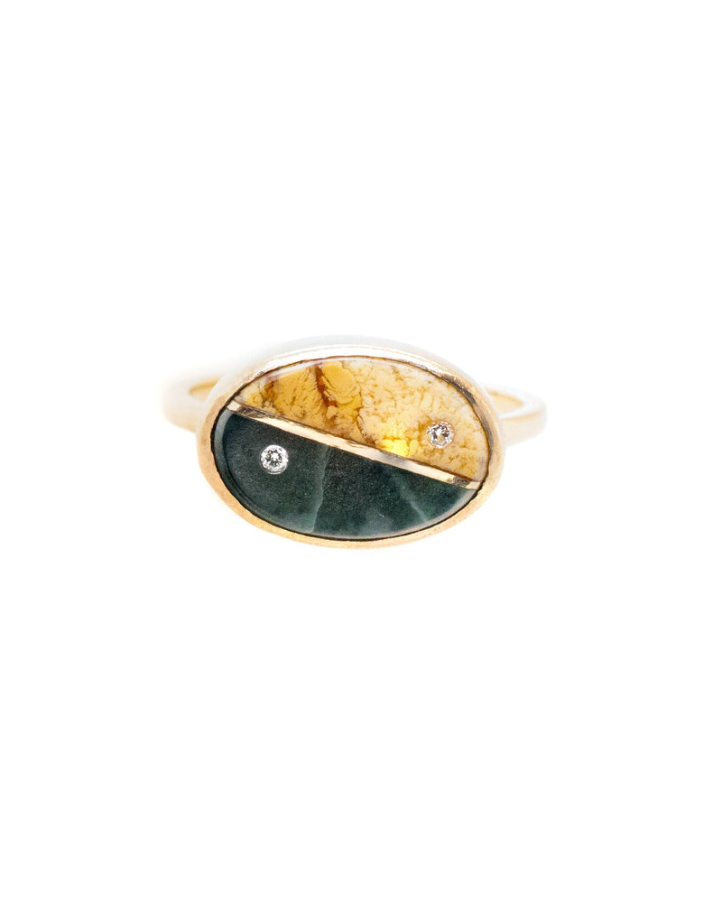 The Yin Yang Elliptical Ring by Karen Luvaas is a gold ring with an oval face, showcasing yellow and dark green stones divided in yin-yang style, each side accented with a small round diamond.